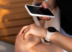 Išmanusis telefonas ir apvalus išmanusis laikrodis ant rankų